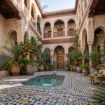 Patio lumineux d'un riad à Marrakech avec bassin et zelliges, illustrant une conciergerie riad Marrakech